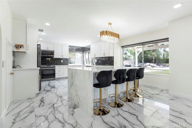 20128 Cavern Ct, Saugus, CA 91390 - kitchen featuring stainless steel appliances, tasteful backsplash, light countertops, a kitchen bar, and white cabinetry