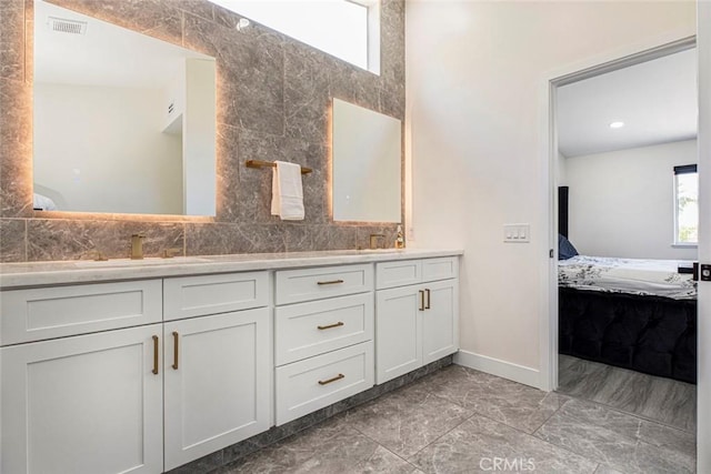 20128 Cavern Ct, Saugus, CA 91390 - ensuite bathroom with double vanity, marble look tile flooring, tasteful backsplash, and baseboards