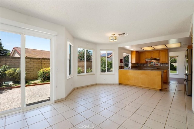 3016 Daphney Ct, Simi Valley, CA 93063 - kitchen with under cabinet range hood, freestanding refrigerator, light tile patterned flooring, healthy amount of natural light, and a textured ceiling