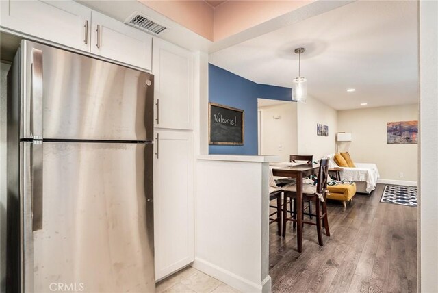 4201 W 5th St Unit 218, Santa Ana, CA 92703 - kitchen featuring freestanding refrigerator, white cabinets, baseboards, light wood finished floors, and hanging light fixtures
