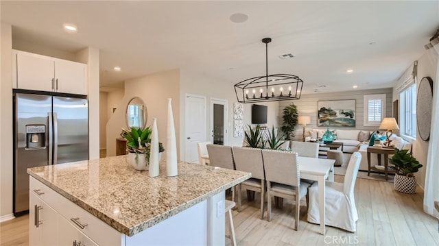 30020 Pomo Canyon Ct, Menifee, CA 92585 - kitchen with stainless steel fridge, a chandelier, open floor plan, white cabinets, and a kitchen island
