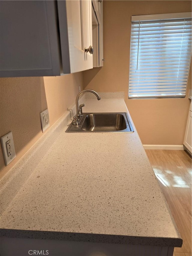400 N Acacia Ave Unit D16, Fullerton, CA 92831 - kitchen featuring a sink, light wood finished floors, light countertops, white cabinets, and baseboards
