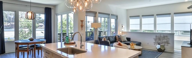 1207 Doheny Way, Dana Point, CA 92629 - kitchen featuring wood finished floors, a chandelier, decorative light fixtures, an island with sink, and light countertops