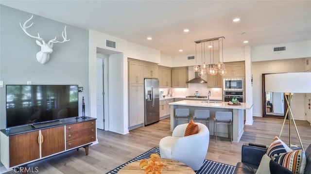 1207 Doheny Way, Dana Point, CA 92629 - kitchen with appliances with stainless steel finishes, wall chimney exhaust hood, light wood-type flooring, light countertops, and a center island with sink