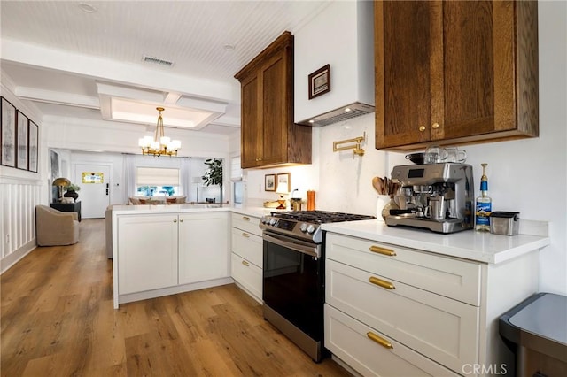 1856 W 43rd St, Los Angeles, CA 90062 - kitchen featuring gas range, a chandelier, light countertops, a peninsula, and light wood finished floors