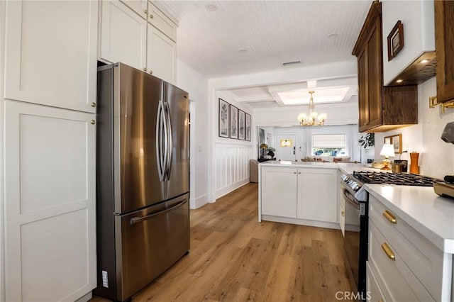 1856 W 43rd St, Los Angeles, CA 90062 - kitchen featuring stainless steel appliances, a peninsula, a chandelier, light countertops, and light wood-style floors