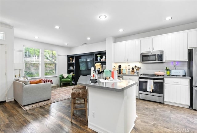 3 Bluff Cove Dr, Aliso Viejo, CA 92656 - kitchen with appliances with stainless steel finishes, open floor plan, white cabinetry, recessed lighting, and a kitchen breakfast bar