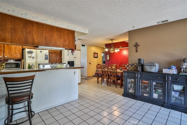 3012 Homer Cir, Jurupa Valley, CA 91752 - kitchen featuring white refrigerator with ice dispenser, a textured ceiling, a chandelier, light tile patterned flooring, and stainless steel microwave
