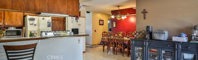 3012 Homer Cir, Jurupa Valley, CA 91752 - kitchen with stainless steel microwave, white refrigerator with ice dispenser, a chandelier, stove, and brown cabinets