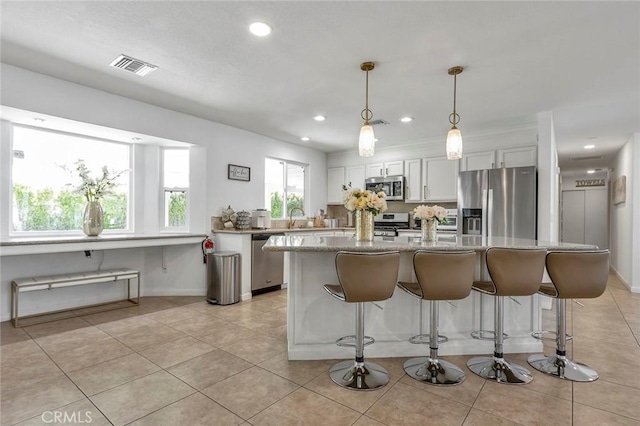 2230 N Volturno Rd, Palm Springs, CA 92262 - kitchen with stainless steel appliances, a kitchen island, a breakfast bar area, a sink, and light tile patterned floors