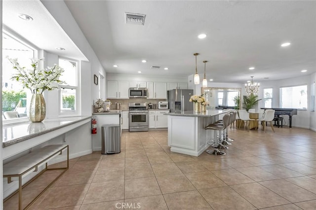 2230 N Volturno Rd, Palm Springs, CA 92262 - kitchen with stainless steel appliances, recessed lighting, white cabinets, a kitchen breakfast bar, and light tile patterned floors