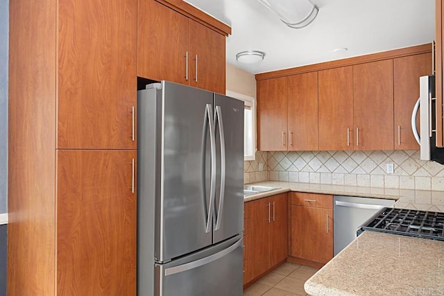 575 7th St # 203, Imperial Beach, CA 91932 - kitchen featuring appliances with stainless steel finishes, decorative backsplash, brown cabinetry, and light tile patterned floors