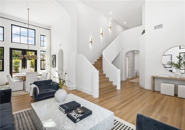 2317 Via Zafiro, San Clemente, CA 92673 - living room featuring arched walkways, a towering ceiling, wood finished floors, stairway, and a chandelier