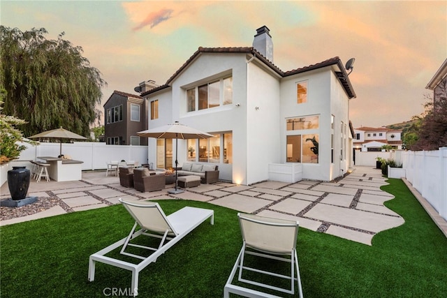 38 Via Sonrisa, San Clemente, CA 92673 - back of house at dusk with a chimney, an outdoor hangout area, a patio, stucco siding, and a tile roof
