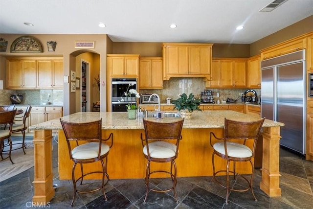 889 Highridge St, Riverside, CA 92506 - kitchen with built in fridge, stainless steel double oven, decorative backsplash, a kitchen island with sink, and light stone counters
