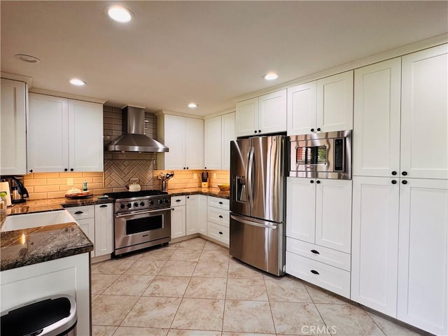 10141 Orange St, Rancho Cucamonga, CA 91737 - kitchen with wall chimney range hood, stainless steel appliances, decorative backsplash, dark stone counters, and white cabinets