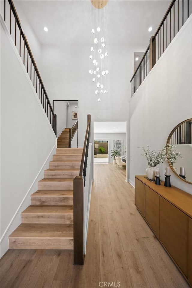 271 Huckleberry, Lake Forest, CA 92630 - stairs featuring a towering ceiling, wood finished floors, baseboards, a chandelier, and recessed lighting