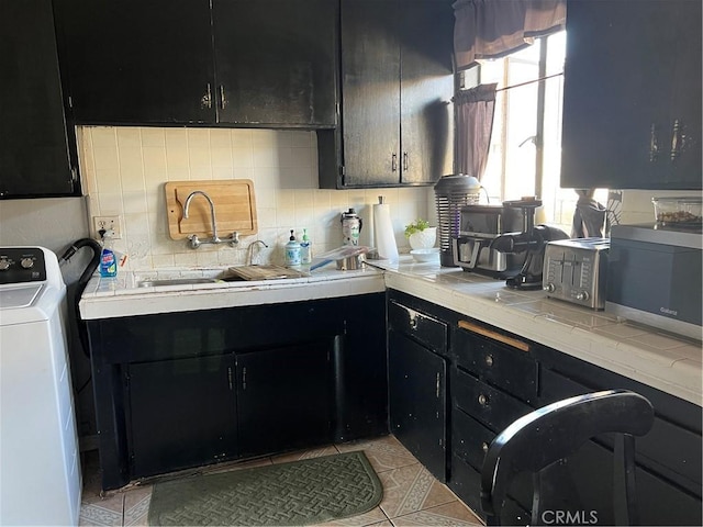 2124 W Civic Center Dr, Santa Ana, CA 92703 - kitchen with washer / clothes dryer, dark cabinetry, stainless steel microwave, and decorative backsplash