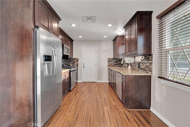 11777 Preston Ln, Yucaipa, CA 92399 - kitchen with appliances with stainless steel finishes, dark brown cabinetry, light wood-type flooring, backsplash, and recessed lighting