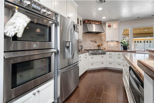 5215 Columbia Way, Lancaster, CA 93536 - kitchen with appliances with stainless steel finishes, wall chimney exhaust hood, backsplash, white cabinetry, and a textured ceiling