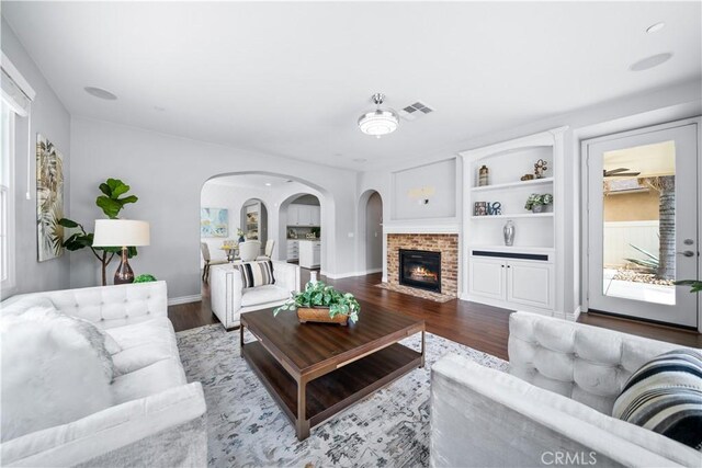 46239 Lone Pine Dr, Temecula, CA 92592 - living area featuring wood finished floors, a brick fireplace, arched walkways, and baseboards
