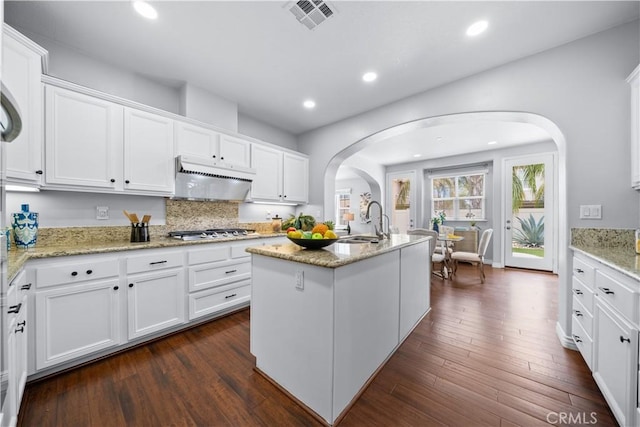 46239 Lone Pine Dr, Temecula, CA 92592 - kitchen featuring arched walkways, a sink, under cabinet range hood, stainless steel gas cooktop, and white cabinets