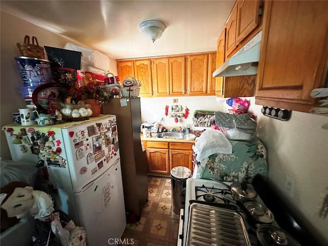 1136 Arapahoe St, Los Angeles, CA 90006 - kitchen with under cabinet range hood, tile patterned floors, freestanding refrigerator, brown cabinetry, and light countertops