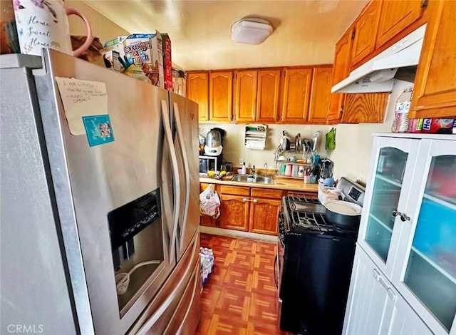 1136 Arapahoe St, Los Angeles, CA 90006 - kitchen with stainless steel fridge, gas range, under cabinet range hood, brown cabinetry, and a sink