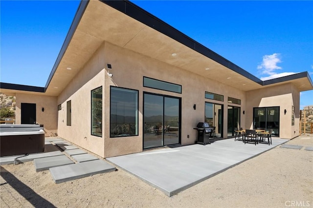 5890 Olema Rd, Yucca Valley, CA 92284 - rear view of house with a hot tub, a patio, and stucco siding