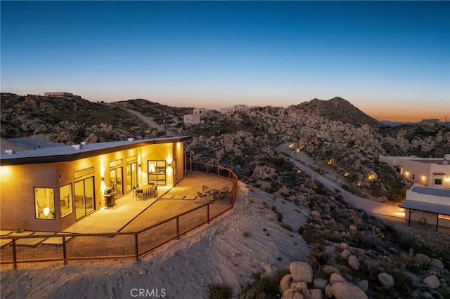 5890 Olema Rd, Yucca Valley, CA 92284 - back of house at dusk featuring a mountain view, a patio, and stucco siding