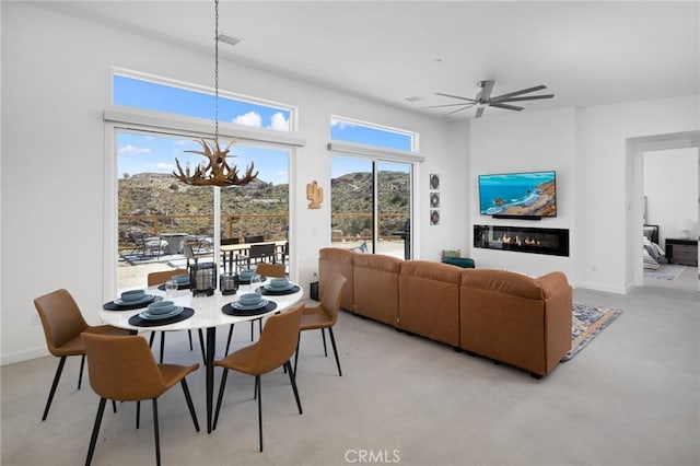 5890 Olema Rd, Yucca Valley, CA 92284 - dining area with a chandelier, ceiling fan, and a glass covered fireplace