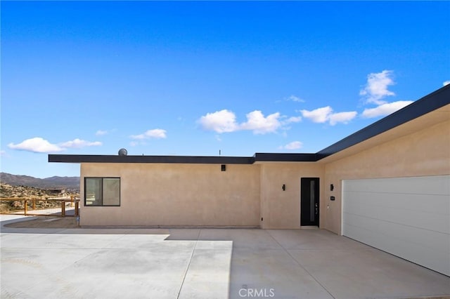 5890 Olema Rd, Yucca Valley, CA 92284 - view of front of home featuring stucco siding, a mountain view, and a garage