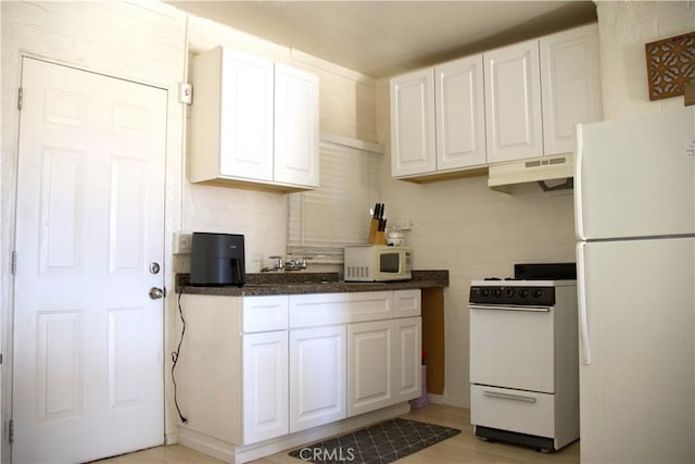 73514 Desert Trail Dr Unit 29, Palms, CA 92277 - kitchen with white appliances, under cabinet range hood, white cabinetry, and dark stone counters