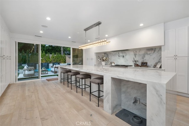 5 Modesto, Irvine, CA 92602 - kitchen with tasteful backsplash, light wood-style flooring, white cabinets, light stone counters, and a spacious island