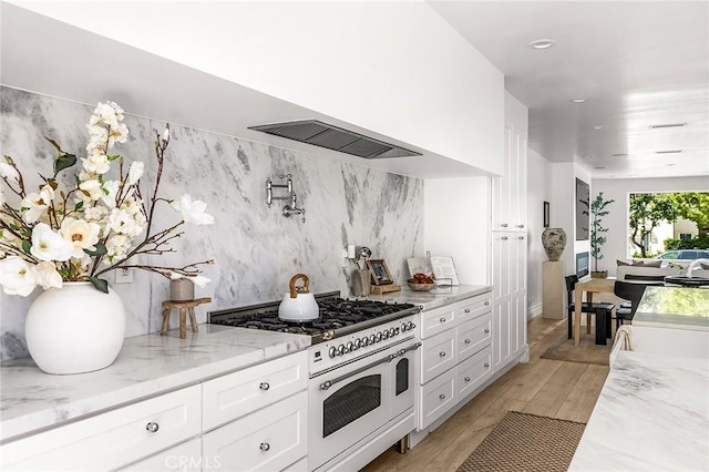 5 Modesto, Irvine, CA 92602 - kitchen with double oven range, white cabinetry, light wood-style flooring, light stone countertops, and recessed lighting