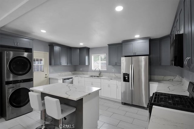 15510 Midcrest Dr, Whittier, CA 90604 - kitchen with stainless steel appliances, stacked washer / drying machine, a sink, light stone countertops, and a kitchen island