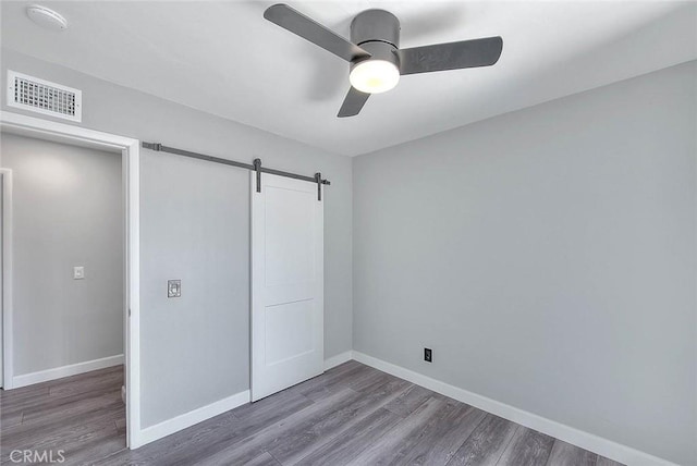 7747 Onyx Ave, Rancho Cucamonga, CA 91730 - unfurnished bedroom featuring wood finished floors, baseboards, a closet, and a barn door