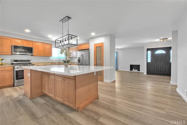 7747 Onyx Ave, Rancho Cucamonga, CA 91730 - kitchen featuring appliances with stainless steel finishes, a center island, light countertops, light wood-style flooring, and plenty of natural light