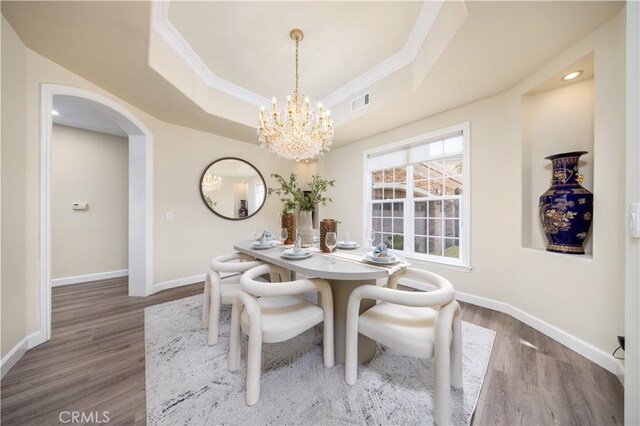 2122 Meteora Way, Rowland Heights, CA 91748 - dining area featuring ornamental molding, wood finished floors, a chandelier, a tray ceiling, and arched walkways