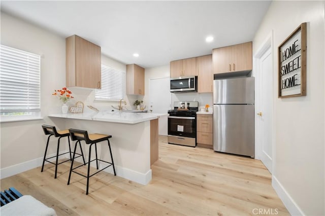 5882 Bowcroft St Unit 2, Los Angeles, CA 90016 - kitchen featuring appliances with stainless steel finishes, light brown cabinets, a peninsula, a kitchen bar, and light countertops