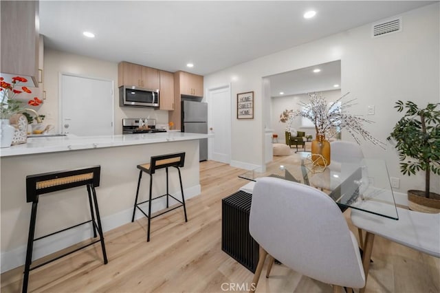 5882 Bowcroft St Unit 2, Los Angeles, CA 90016 - kitchen with stainless steel appliances, a peninsula, light wood finished floors, a breakfast bar area, and baseboards