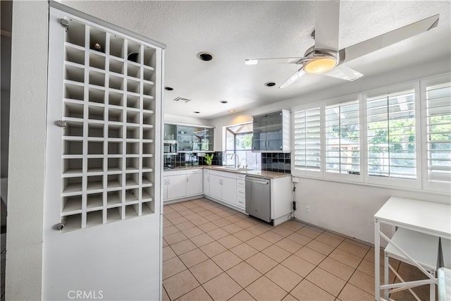 2110 Hathaway Pl, Riverside, CA 92506 - kitchen with dishwasher, a sink, light tile patterned floors, a ceiling fan, and white cabinetry