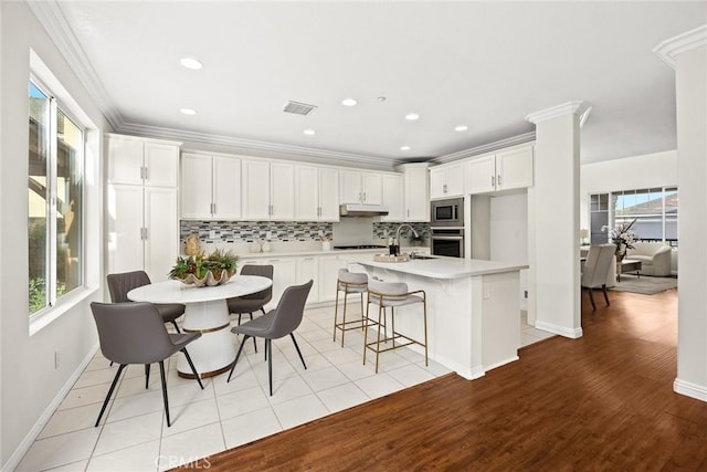 3612 Skylark Way, Brea, CA 92823 - kitchen featuring appliances with stainless steel finishes, under cabinet range hood, tasteful backsplash, light countertops, and white cabinets
