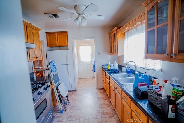 317 N 19th St, Montebello, CA 90640 - kitchen with stainless steel gas stove, a sink, a ceiling fan, brown cabinetry, and glass insert cabinets