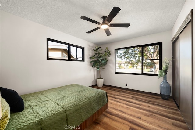 1409 N Midsite Ave, Covina, CA 91722 - bedroom with wood finished floors, a textured ceiling, multiple windows, a closet, and a ceiling fan