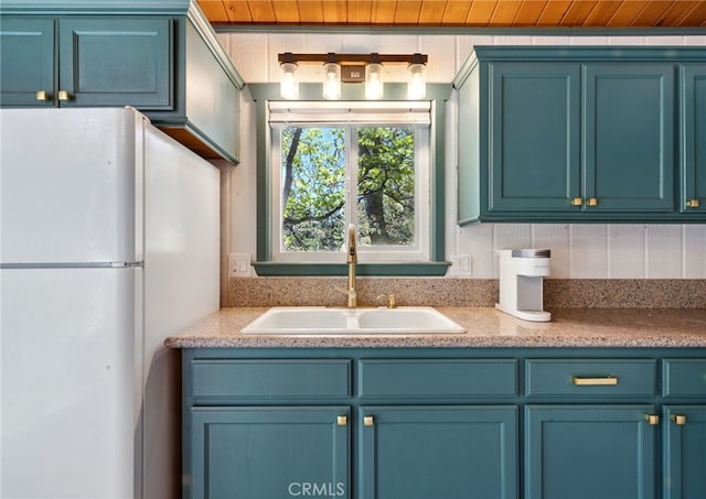 609 Dahlia Dr, Green Valley Lake, CA 92341 - kitchen featuring freestanding refrigerator, a sink, blue cabinetry, and light countertops