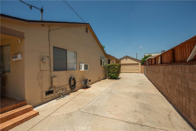 14127 Daubert St, San Fernando, CA 91340 - view of home's exterior featuring stucco siding, an outdoor structure, and a wall unit AC