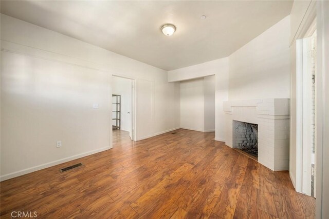 8740 El Camino Real Unit A, Atascadero, CA 93422 - unfurnished living room with wood finished floors, a brick fireplace, and baseboards