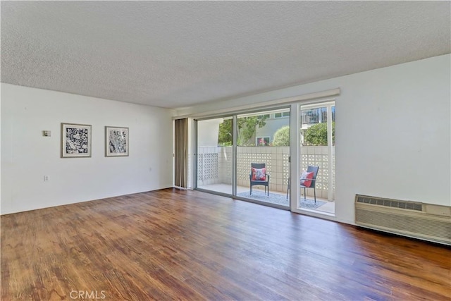 382 Avenida Castilla Unit B, Laguna Woods, CA 92637 - unfurnished room featuring wood finished floors, a textured ceiling, and an AC wall unit