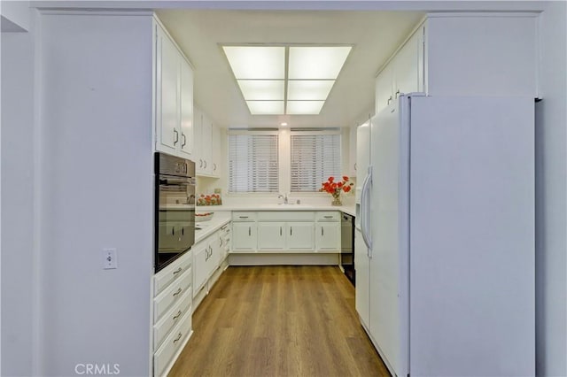 382 Avenida Castilla Unit B, Laguna Woods, CA 92637 - kitchen with black appliances, wood finished floors, and white cabinetry